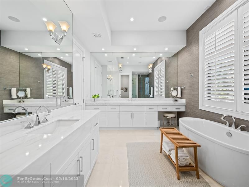 Luxurious primary bathroom, complete with double vanities, a freestanding tub, a private toilet room, and a spacious shower
