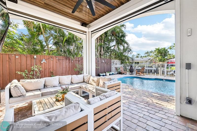 This spacious covered patio offers abundant seating and dining areas, ideal for effortless outdoor entertaining. Featuring custom ceiling paneling with built-in lighting and fans, the space is both stylish and functional. Three remote-controlled hurricane screens provide shade, privacy, and protection for the areas facing the water, pool, and summer kitchen.