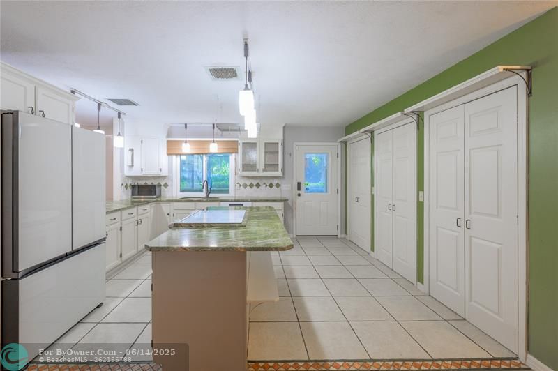 At the heart of the home, the kitchen showcases granite countertops, a breakfast bar, a pass-through window to the summer kitchen, and an impressive amount of storage with three pantry closets. A newer refrigerator and dishwasher (approx. 2–3 years old), pot rack, and microwave are also included.