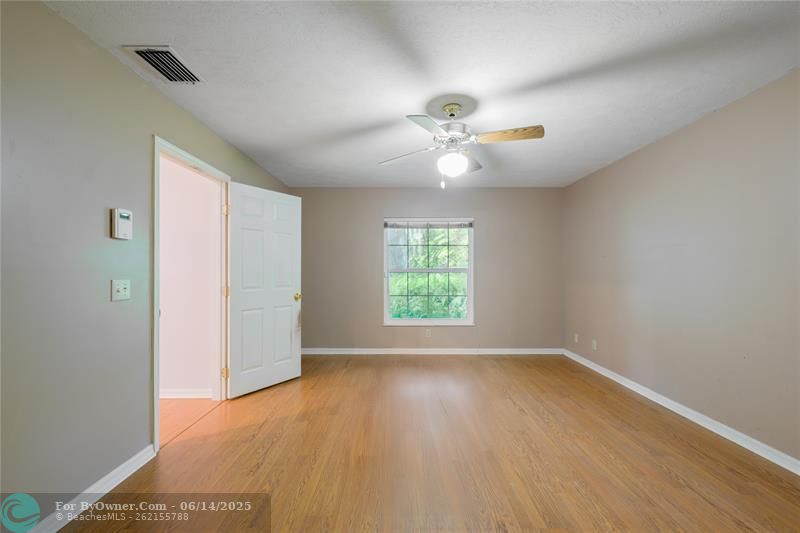 The split floorplan provides excellent separation of space, with the updated primary suite tucked away for added privacy. It includes a walk-in shower, double vanities with Corian counters, and a pocket door for extra seclusion.